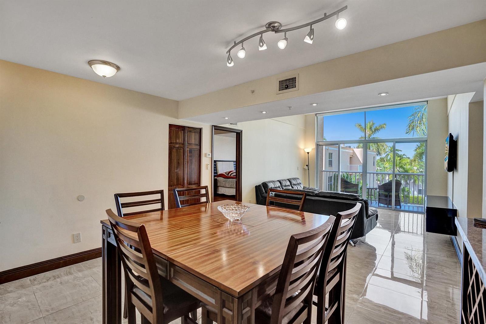 A dining area with a wooden table leads into a living room with floor-to-ceiling windows — 1350 SE 3rd Avenue # 406, Dania Beach FL 33004, DANIA BEACH, FL