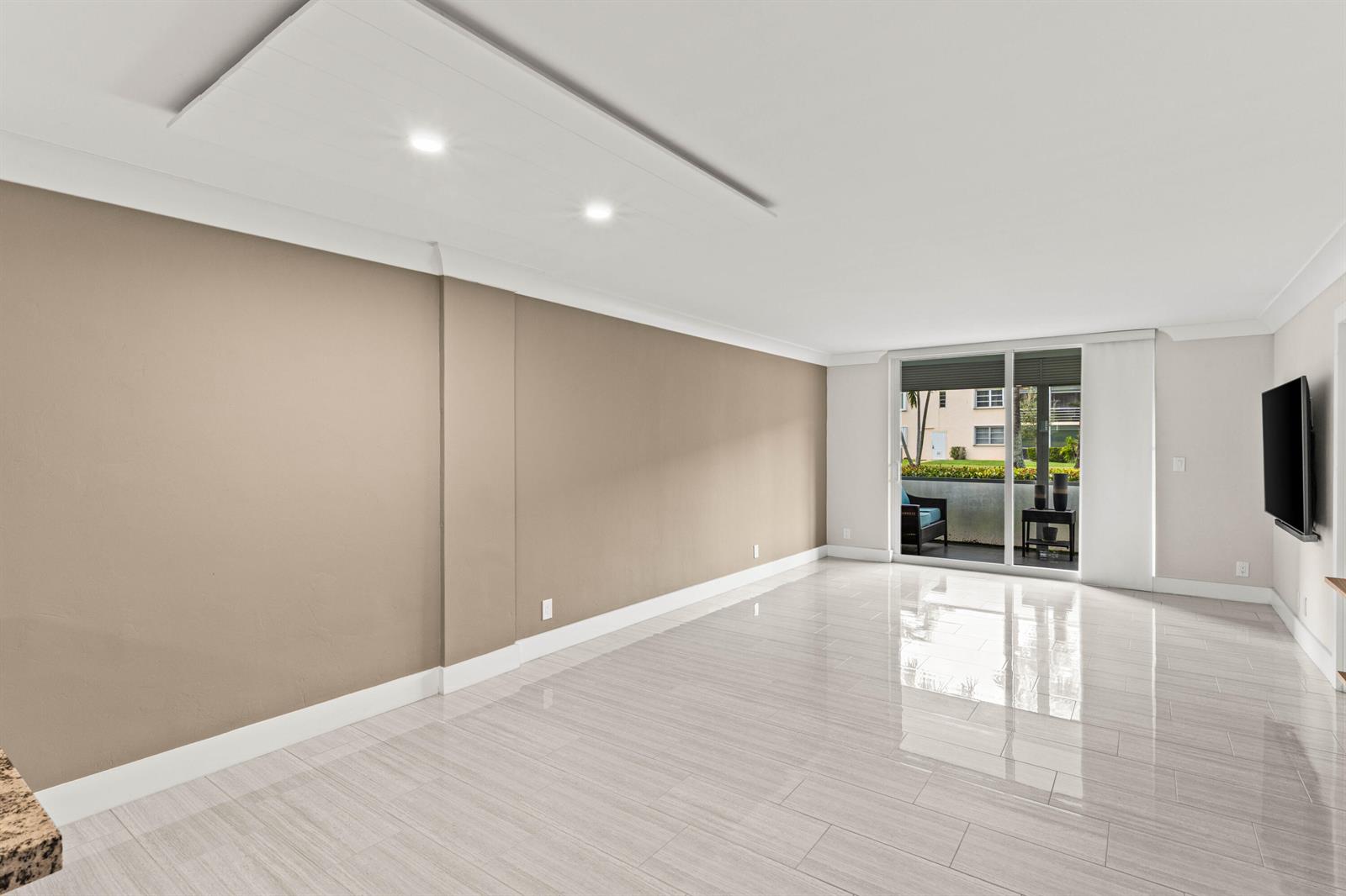 A living room with beige walls, glossy tile flooring, recessed lighting, and a sliding glass door — 4502 N Federal Highway # 144e, Lighthouse Point FL 33064, LIGHTHOUSE POINT, FL