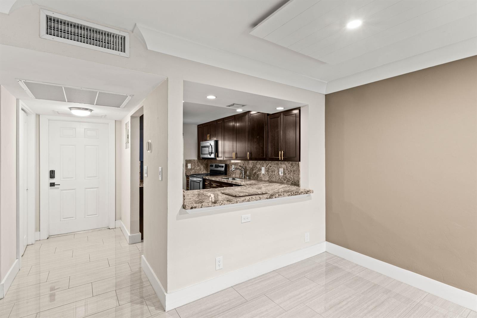 A kitchen with dark cabinets and granite countertops is visible through a pass-through window — 4502 N Federal Highway # 144e, Lighthouse Point FL 33064, LIGHTHOUSE POINT, FL