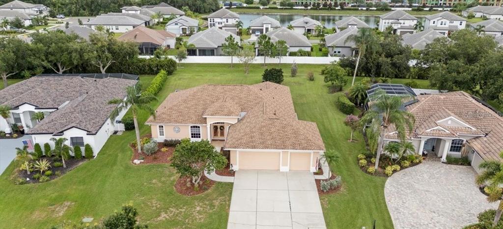 An aerial view shows three suburban houses with tiled roofs and driveways in a neighborhood — 3710 LITTLE COUNTRY ROAD, PARRISH, FL