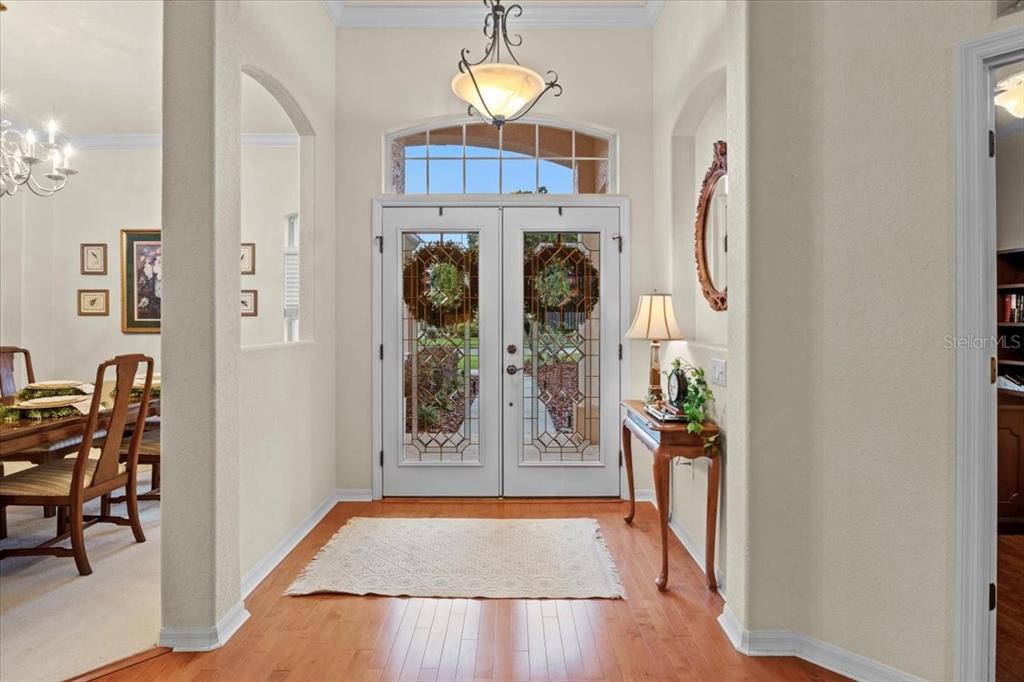 A bright entryway features double glass-paneled doors, hardwood flooring, and a decorative chandelier — 3710 LITTLE COUNTRY ROAD, PARRISH, FL