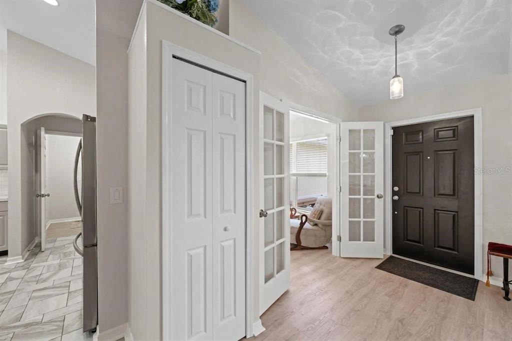 An entryway features a black front door, French doors, a closet, and light wood flooring — 5262 RHAPSODY AVENUE, NORTH PORT, FL