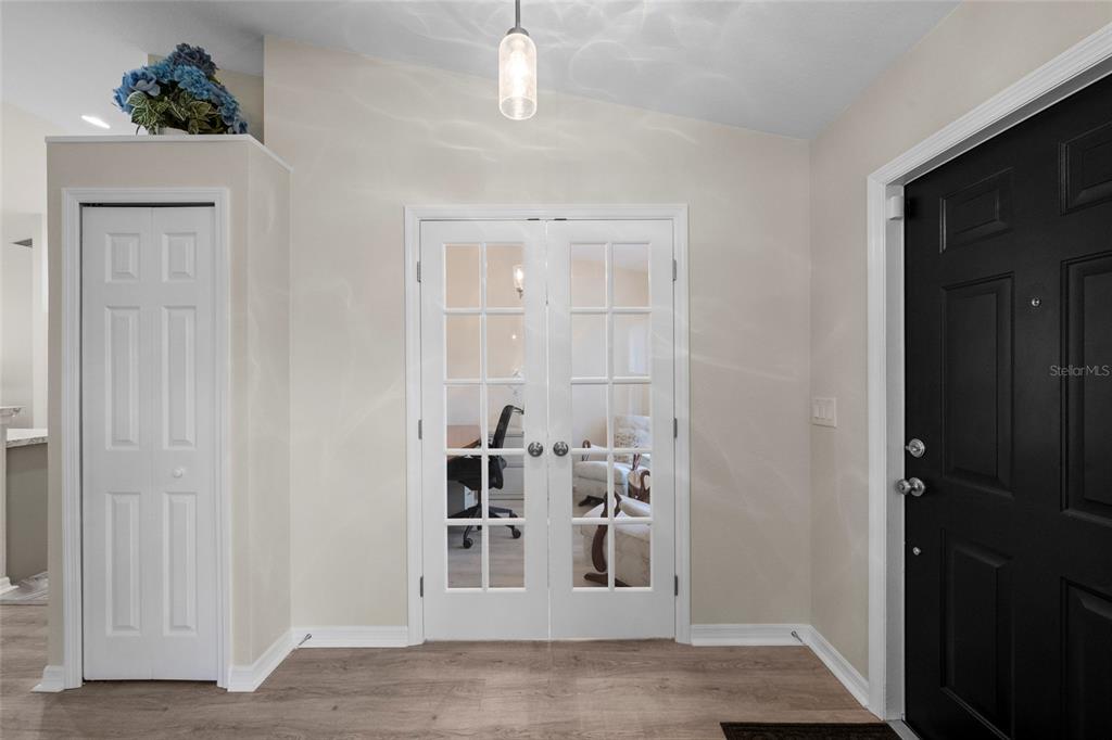 An entryway features a black front door, white French doors, and a white closet door — 5262 RHAPSODY AVENUE, NORTH PORT, FL