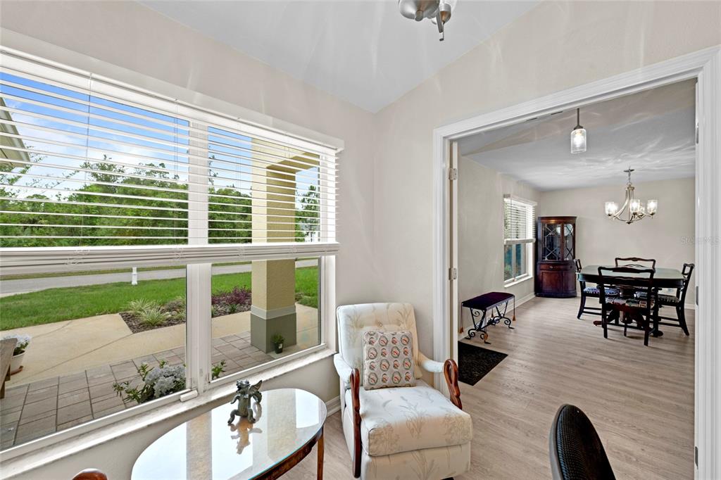 A sunroom with a chair and table overlooks a patio, leading into a dining room — 5262 RHAPSODY AVENUE, NORTH PORT, FL