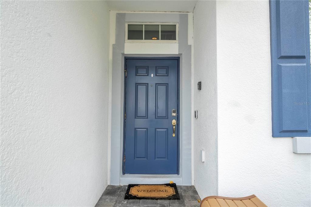 A blue front door with a transom window and a welcome mat on a porch — 1646 MOON VALLEY DRIVE, DAVENPORT, FL