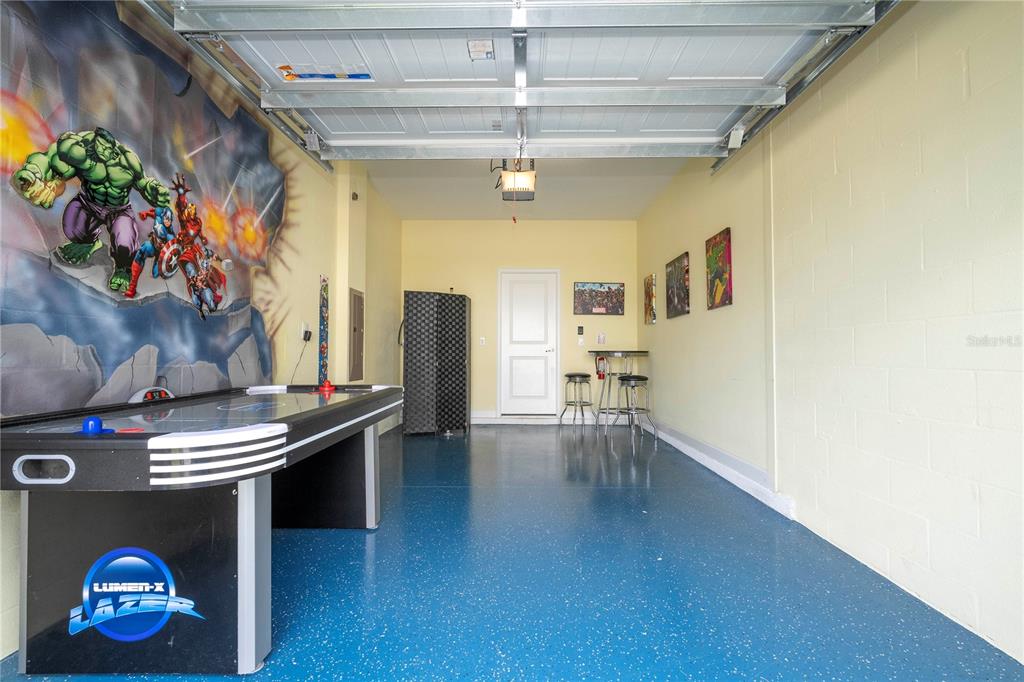 A garage converted into a game room with an air hockey table and wall murals — 1646 MOON VALLEY DRIVE, DAVENPORT, FL