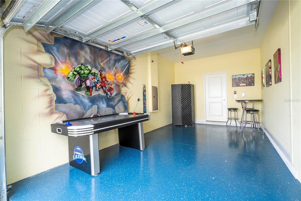 A garage converted into a game room with an air hockey table and Marvel wall mural — 1646 MOON VALLEY DRIVE, DAVENPORT, FL
