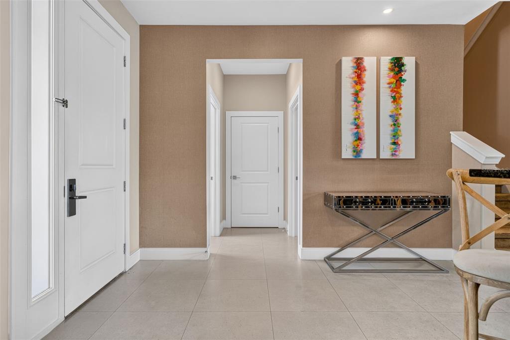 A bright entryway features light tile floors, a console table, and two colorful vertical paintings — 3202 BRASILIA AVENUE, KISSIMMEE, FL