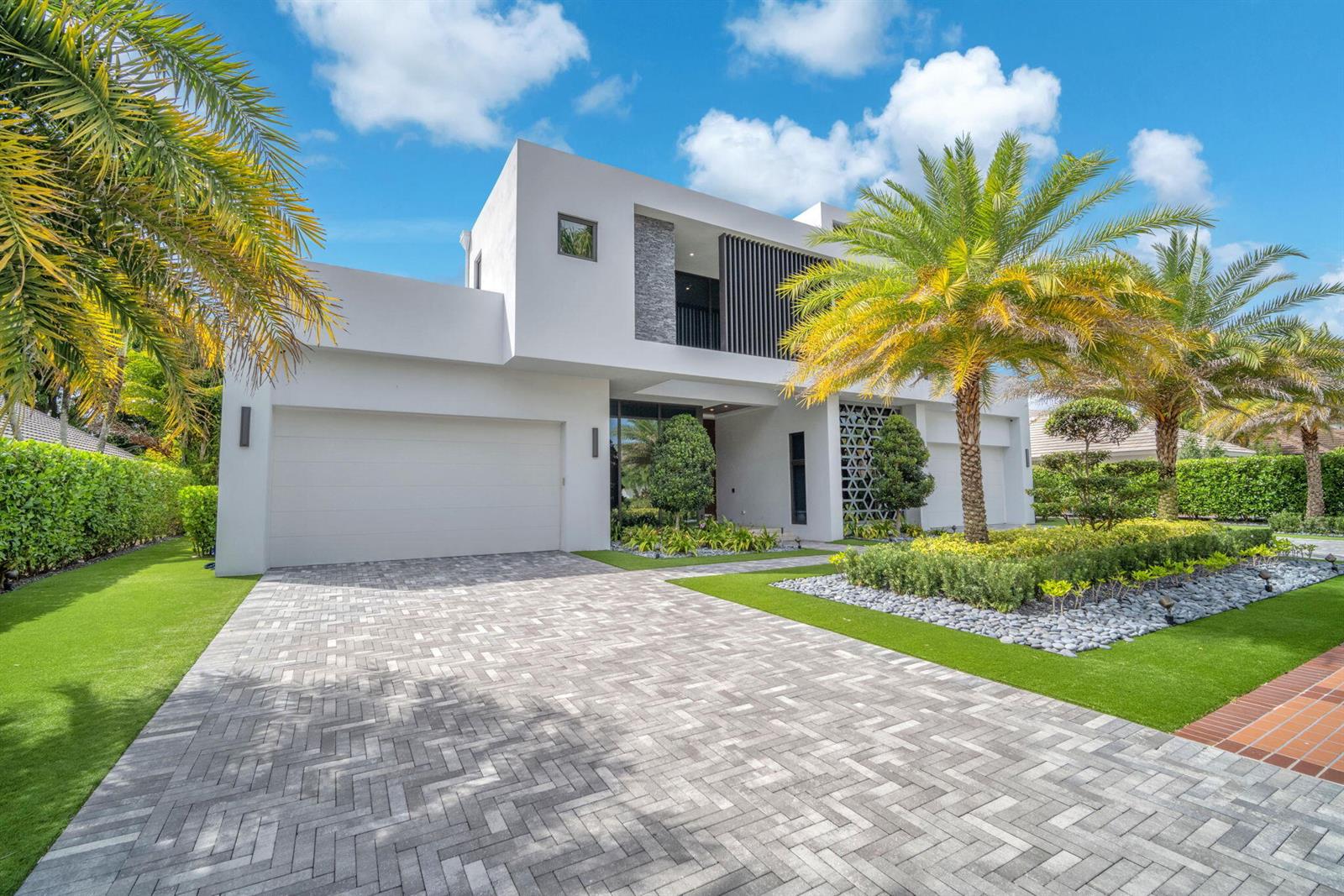 A modern two-story house features a paved driveway, palm trees, and a white exterior — 17787 Scarsdale Way, Boca Raton FL 33496, BOCA RATON, FL