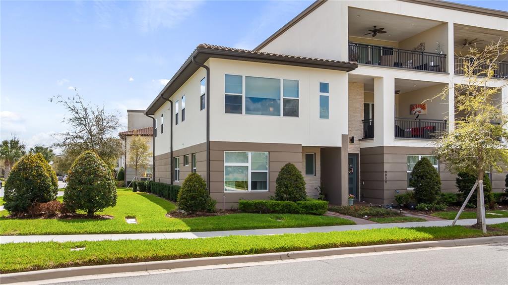 A three-story residential building with a tan and white exterior, balconies, and landscaped front yard — 9940 BUCKLOW HILL DRIVE, ORLANDO, FL