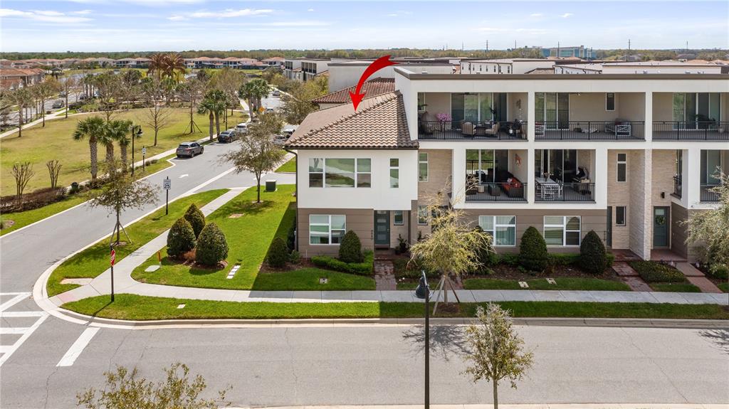 An exterior view of a multi-story townhouse with a tiled roof and a corner balcony — 9940 BUCKLOW HILL DRIVE, ORLANDO, FL