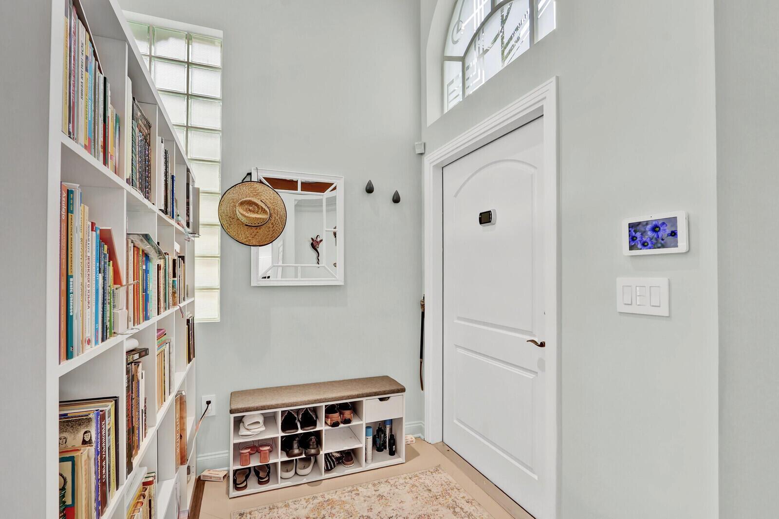 An entryway features a white bookshelf, a shoe storage bench, a mirror, and a front door — 2063 Cezanne Road, West Palm Beach FL 33409, WEST PALM BEACH, FL