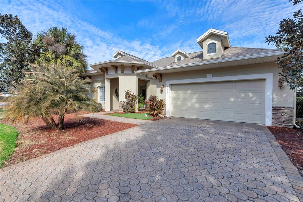 A single-story house with a paved driveway, two-car garage, and a palm tree in front — 5203 GROVE MANOR, LADY LAKE, FL