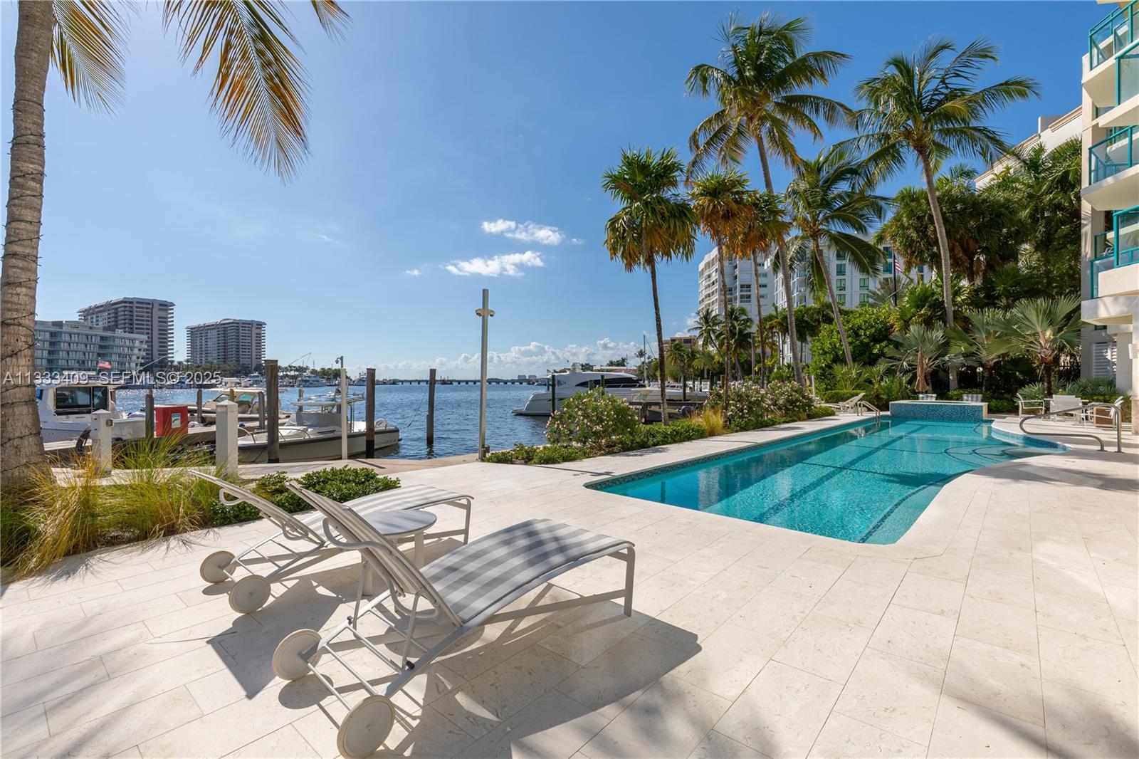 A swimming pool sits on a stone patio next to a marina with palm trees — 1660 W Glencoe St # 302, Coconut Grove FL 33133, COCONUT GROVE, FL