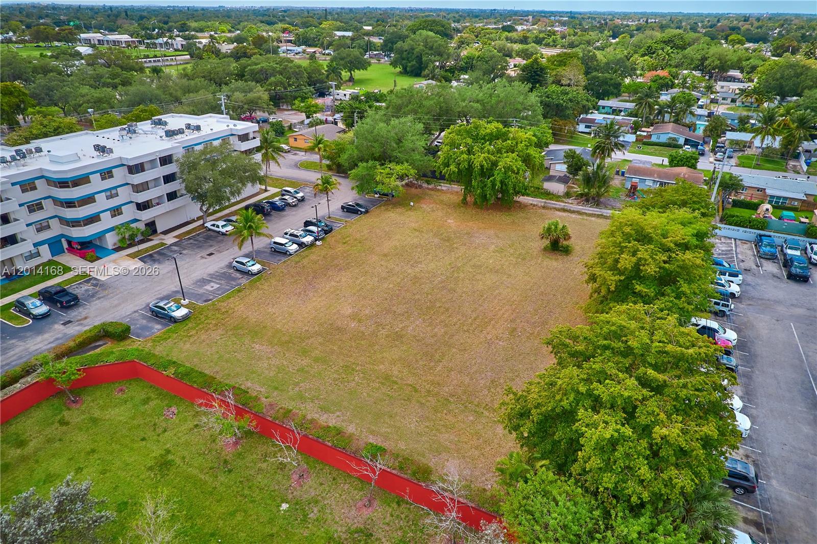 An aerial view shows a vacant, rectangular grassy lot bordered by parking lots and trees — 0 N 61  Avenue, Hollywood FL 33024, HOLLYWOOD, FL