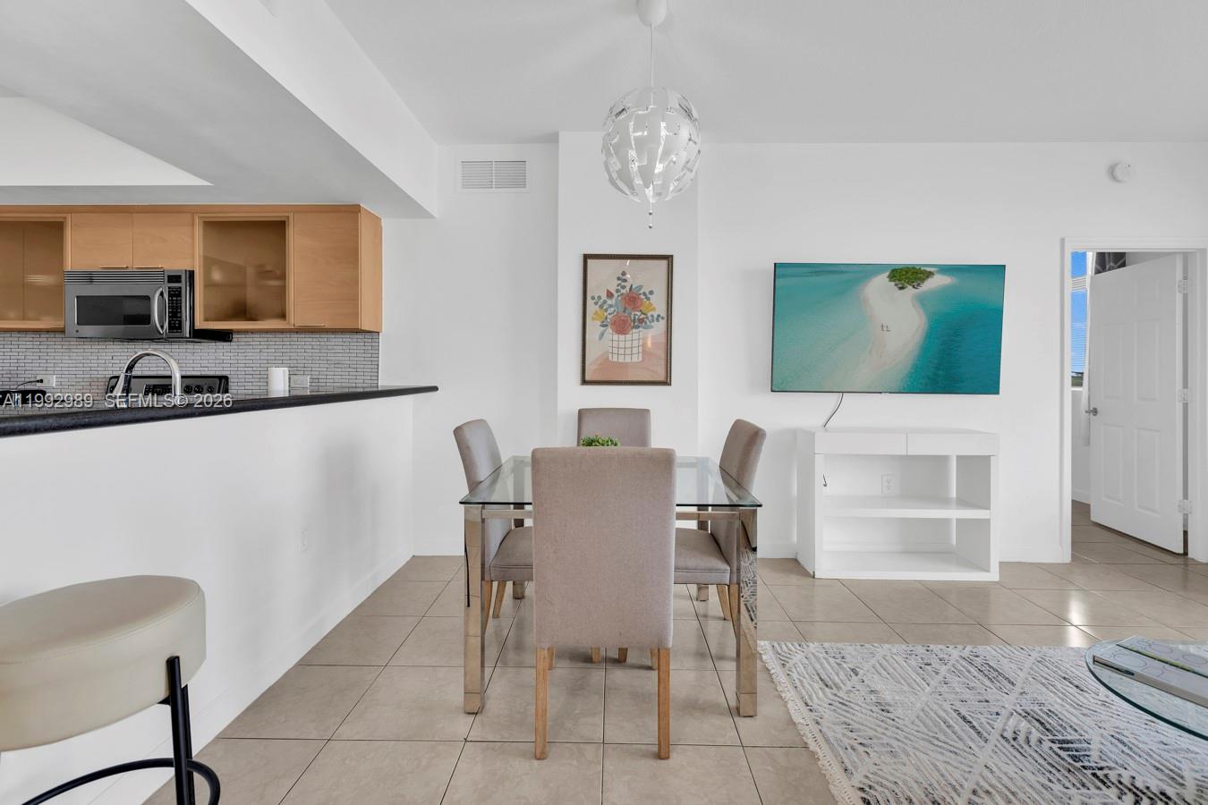 A dining area with a glass table, four chairs, and a wall-mounted television — 140 S Dixie Hwy # 403, Hollywood FL 33020, HOLLYWOOD, FL
