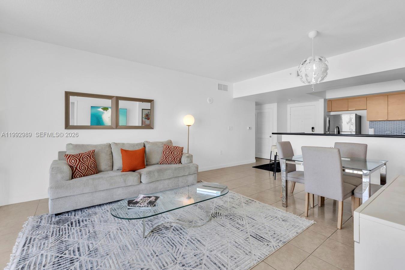 A living and dining area features a beige sofa, glass coffee table, and tile flooring — 140 S Dixie Hwy # 403, Hollywood FL 33020, HOLLYWOOD, FL