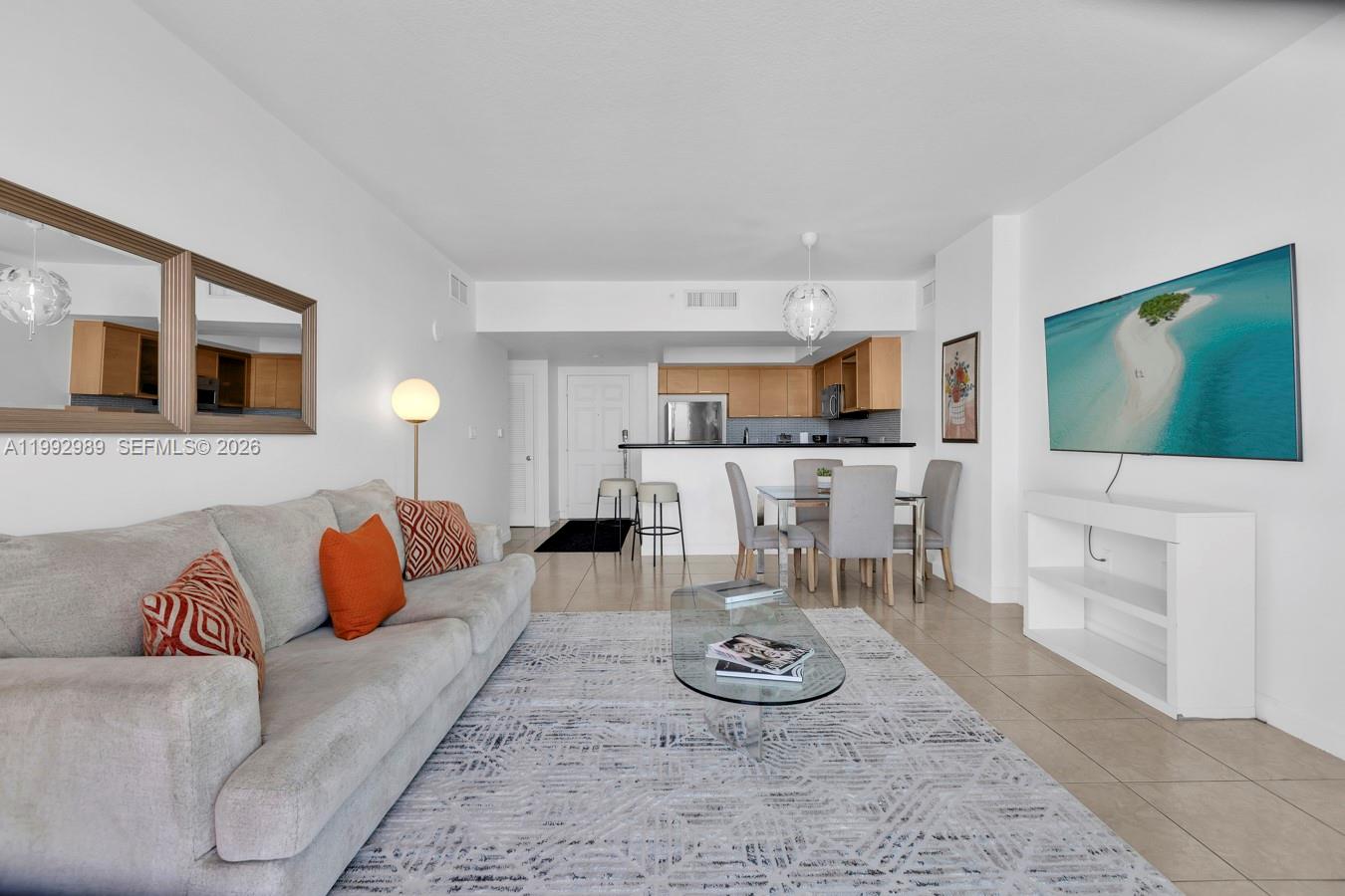 A living room with a grey sofa, glass coffee table, and an open kitchen area — 140 S Dixie Hwy # 403, Hollywood FL 33020, HOLLYWOOD, FL