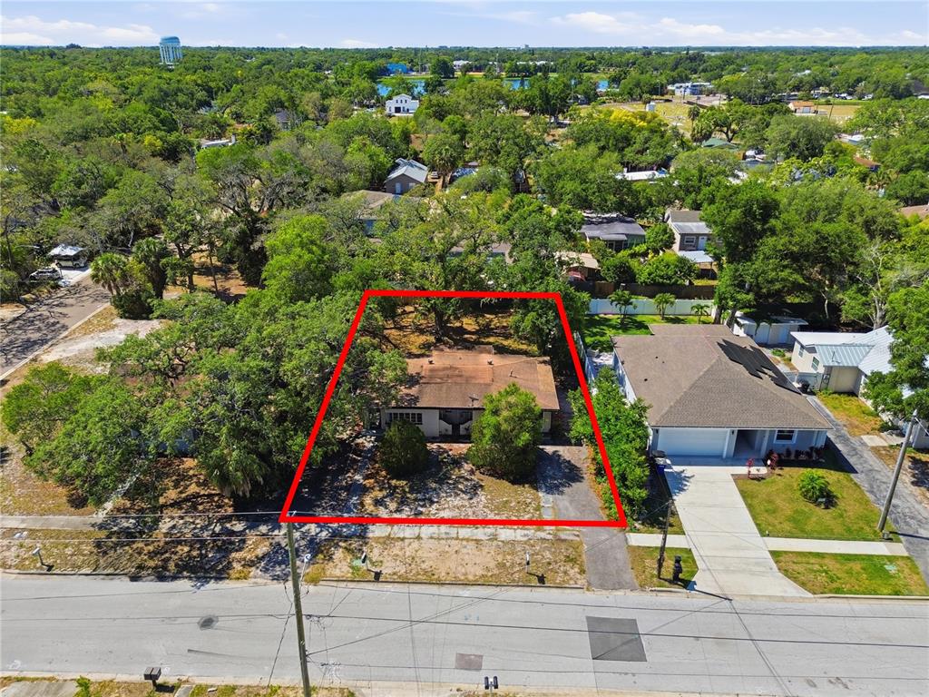 An aerial view shows a single-story house with a brown roof on a wooded lot — 831 GRAND CENTRAL STREET, CLEARWATER, FL