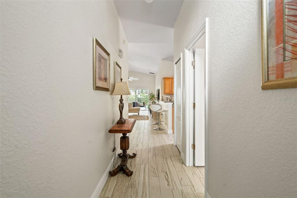 A hallway with light-colored tile flooring leads toward an open kitchen and living area — 17650 WOODCREST WAY, CLERMONT, FL