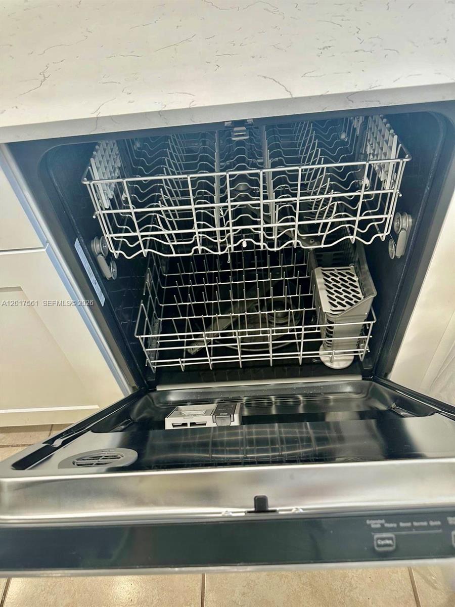 An open dishwasher with two racks is installed under a white countertop — 2301 Wilson St # A, Hollywood FL 33020, HOLLYWOOD, FL