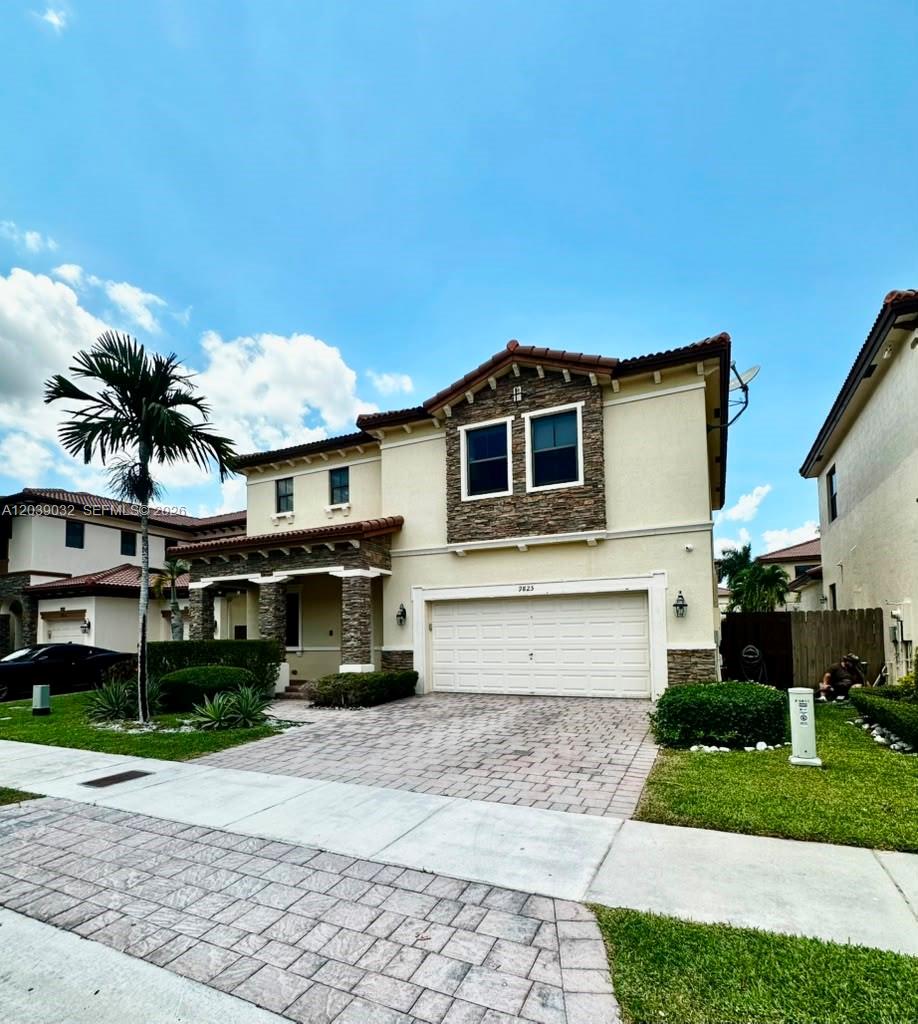A two-story suburban house features a stone-accented facade, a two-car garage, and a paved driveway — 9825 NW 86th Ter, Doral FL 33178, DORAL, FL