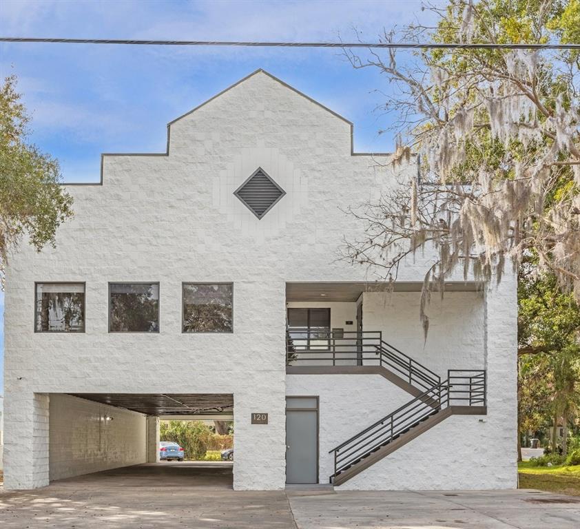 A two-story white building features a ground-level parking area, an exterior staircase, and a diamond-shaped vent — 120 E MARKS STREET UNIT 200, ORLANDO, FL