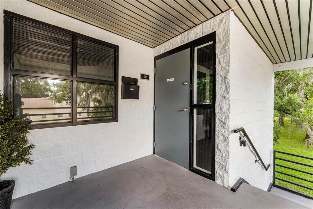 An exterior view of a building entrance with a grey door, window, and metal railing — 120 E MARKS STREET UNIT 200, ORLANDO, FL