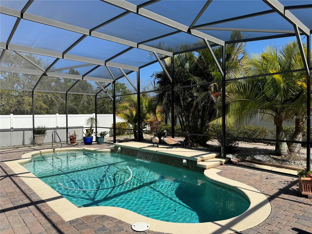 A screened-in swimming pool with a waterfall feature and palm trees in the background — 2127 BRISTOL GRANDE WAY, ORLANDO, FL