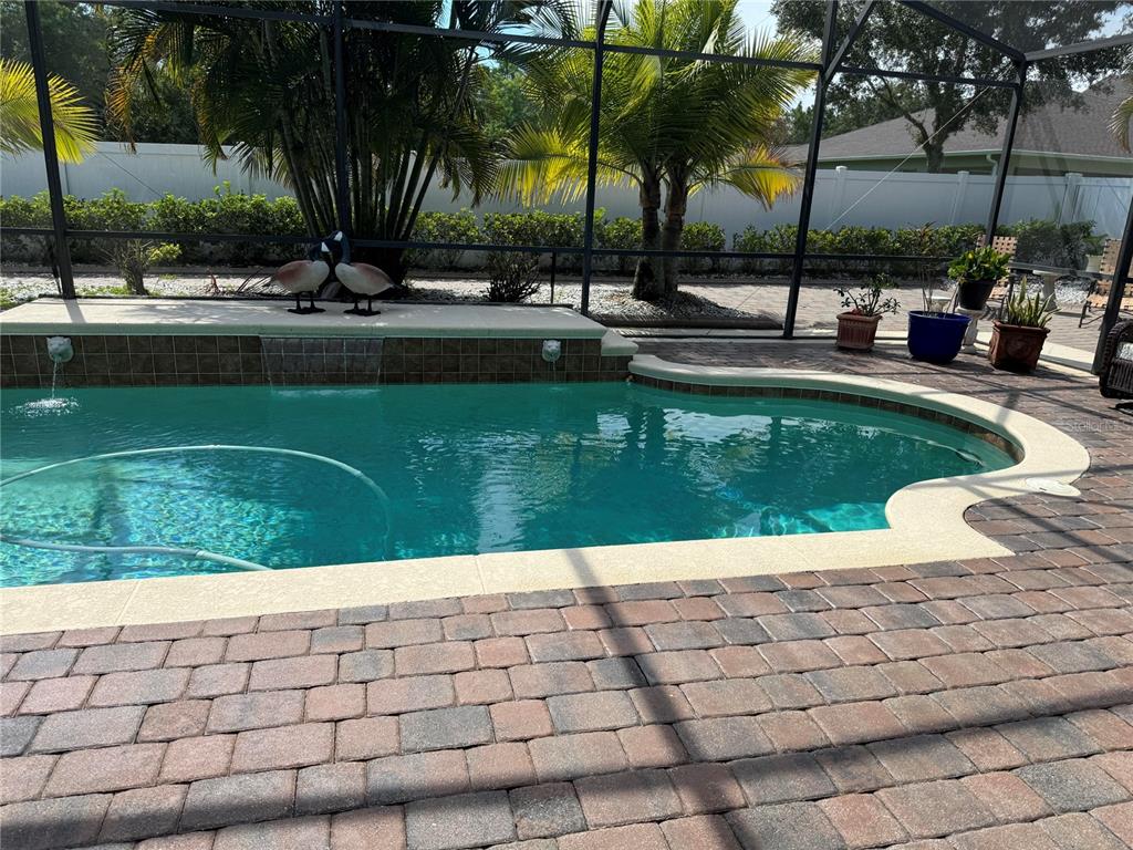 A swimming pool with a water feature and paver deck enclosed by a screen cage — 2127 BRISTOL GRANDE WAY, ORLANDO, FL