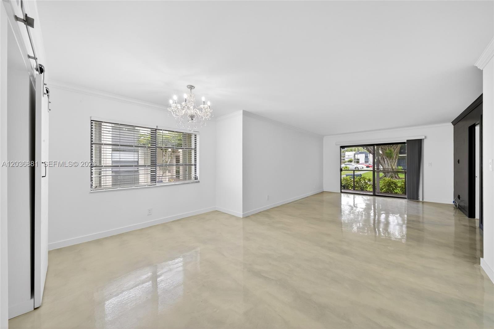 A bright, empty room features white walls, a crystal chandelier, and polished concrete flooring — 265 SE 10th St # 1C, Deerfield Beach FL 33441, DEERFIELD BEACH, FL