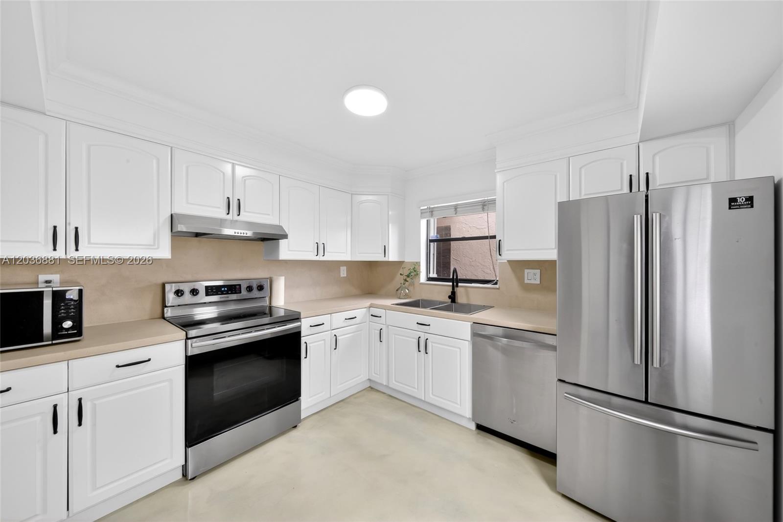 A kitchen features white cabinets, stainless steel appliances, and light-colored countertops — 265 SE 10th St # 1C, Deerfield Beach FL 33441, DEERFIELD BEACH, FL