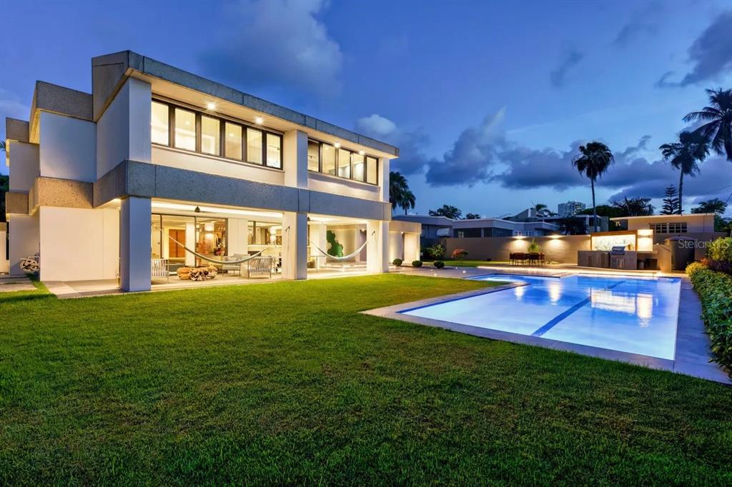 A modern two-story house with a backyard pool and lawn at dusk — 1920 Petunia St URB. SANTA MARIA, SAN JUAN, PR