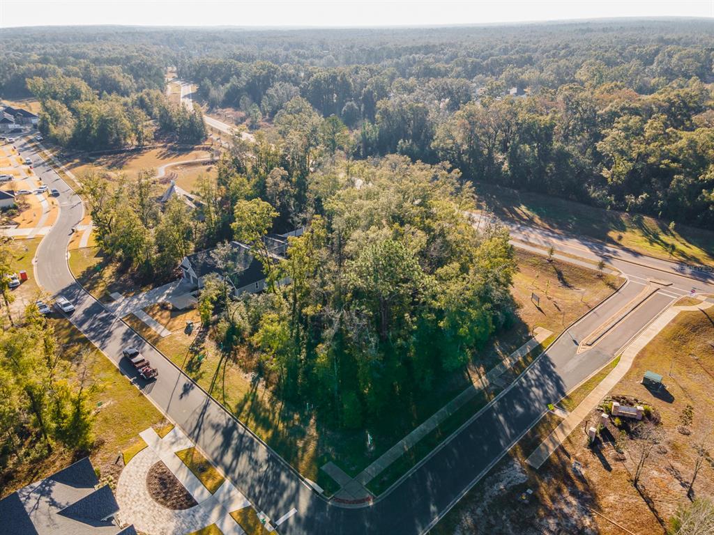 An aerial view shows a wooded corner lot in a residential neighborhood with paved streets — 14117 SW 7TH PLACE, NEWBERRY, FL