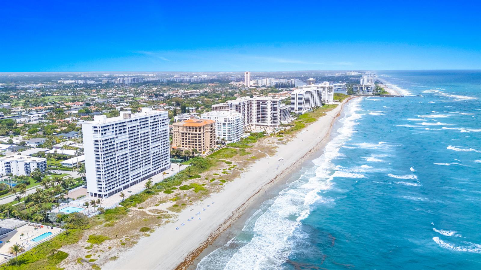 An aerial view shows high-rise apartment buildings along a sandy beach and the ocean — 2600 S Ocean Boulevard, Boca Raton FL 33432, BOCA RATON, FL