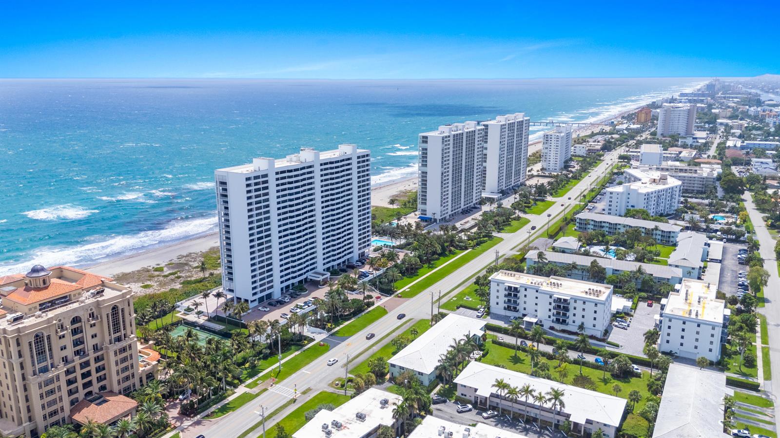 An aerial view shows high-rise apartment buildings along a sandy beach and coastal road — 2600 S Ocean Boulevard, Boca Raton FL 33432, BOCA RATON, FL