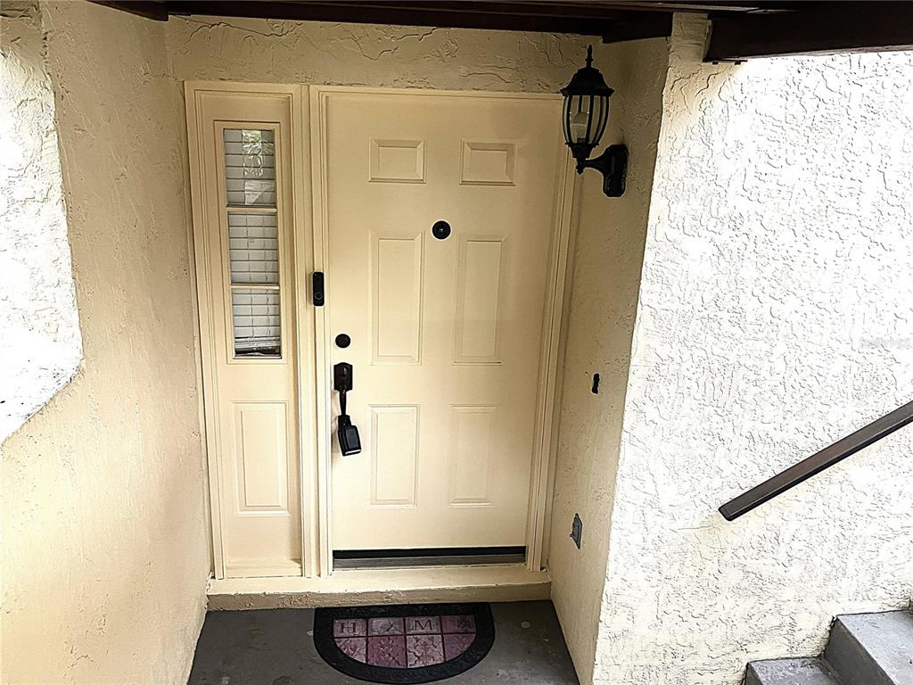A cream-colored front door with a side window light and a black porch lamp — 956 5TH STREET UNIT 9A, CLERMONT, FL