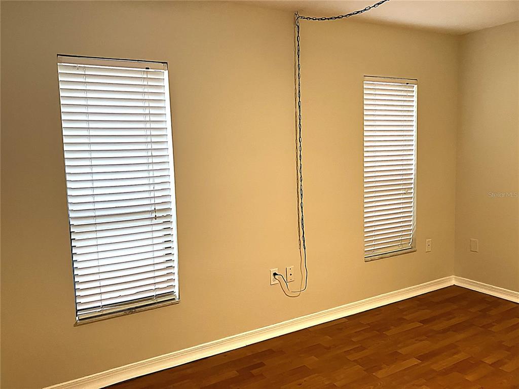 An empty room features wood-look flooring, two windows with blinds, and a hanging metal chain — 956 5TH STREET UNIT 9A, CLERMONT, FL