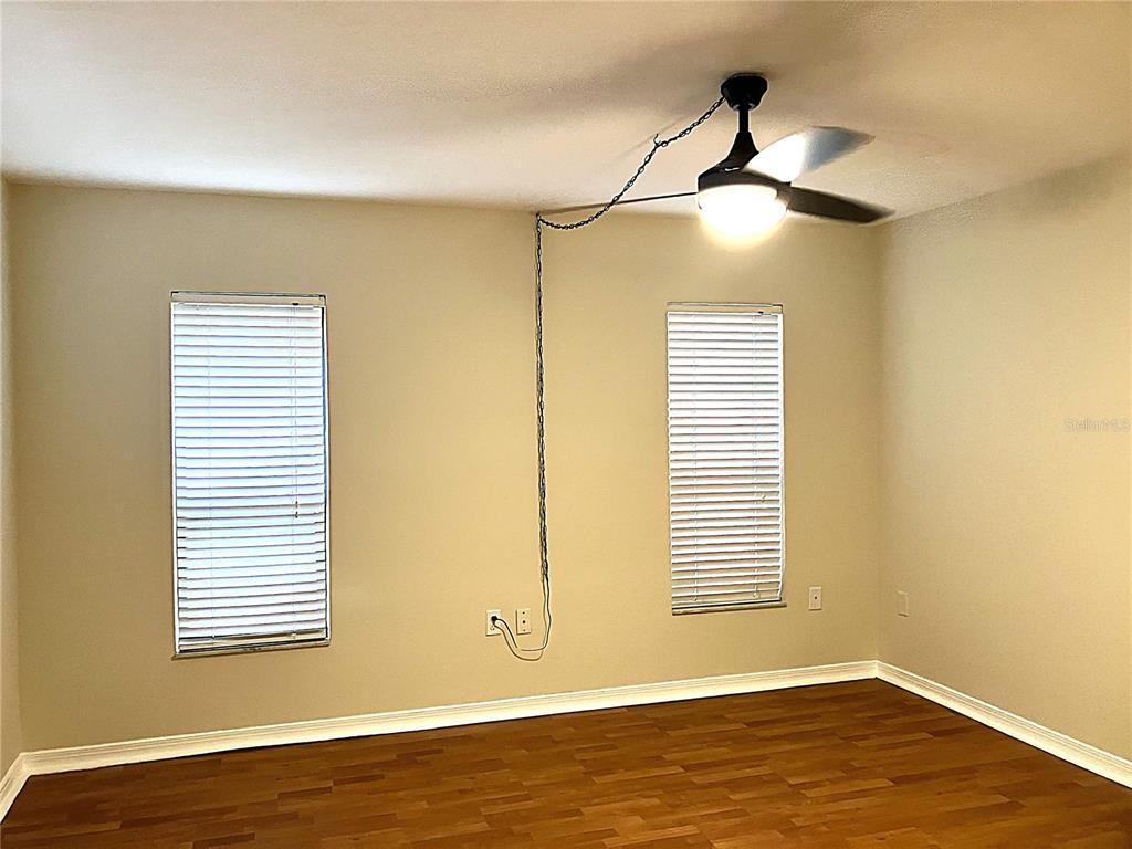 An empty room features wood-look flooring, two windows with blinds, and a ceiling fan — 956 5TH STREET UNIT 9A, CLERMONT, FL