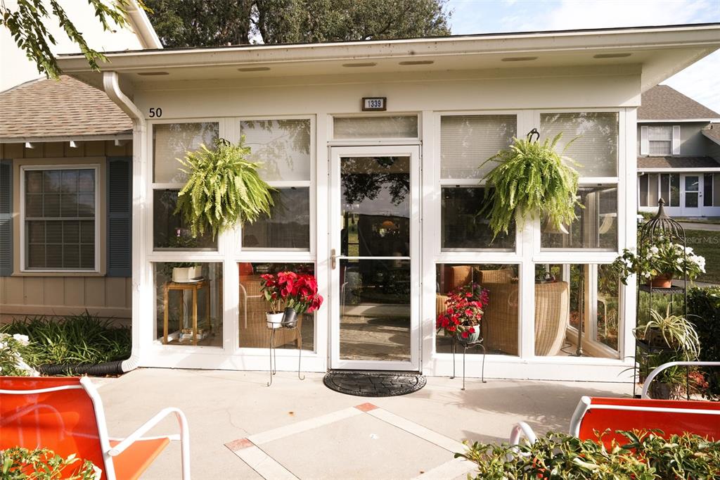A sunroom with white frames and a glass door sits on a concrete patio — 1339 VILLA LANE UNIT 50, APOPKA, FL