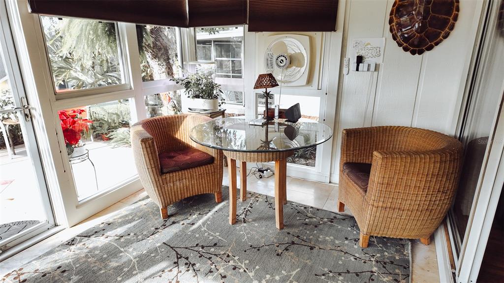 A sunroom features a glass-topped table, two wicker chairs, and a patterned area rug — 1339 VILLA LANE UNIT 50, APOPKA, FL
