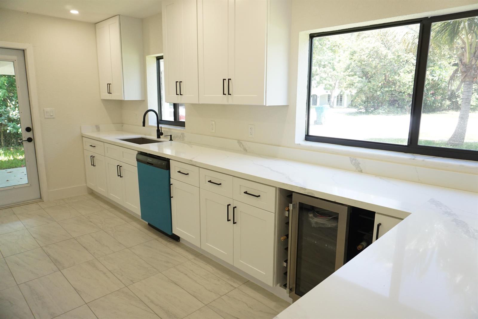 A kitchen features white cabinets, quartz countertops, a blue dishwasher, and a wine cooler — 310 SW 1st Avenue, Boynton Beach FL 33435, BOYNTON BEACH, FL