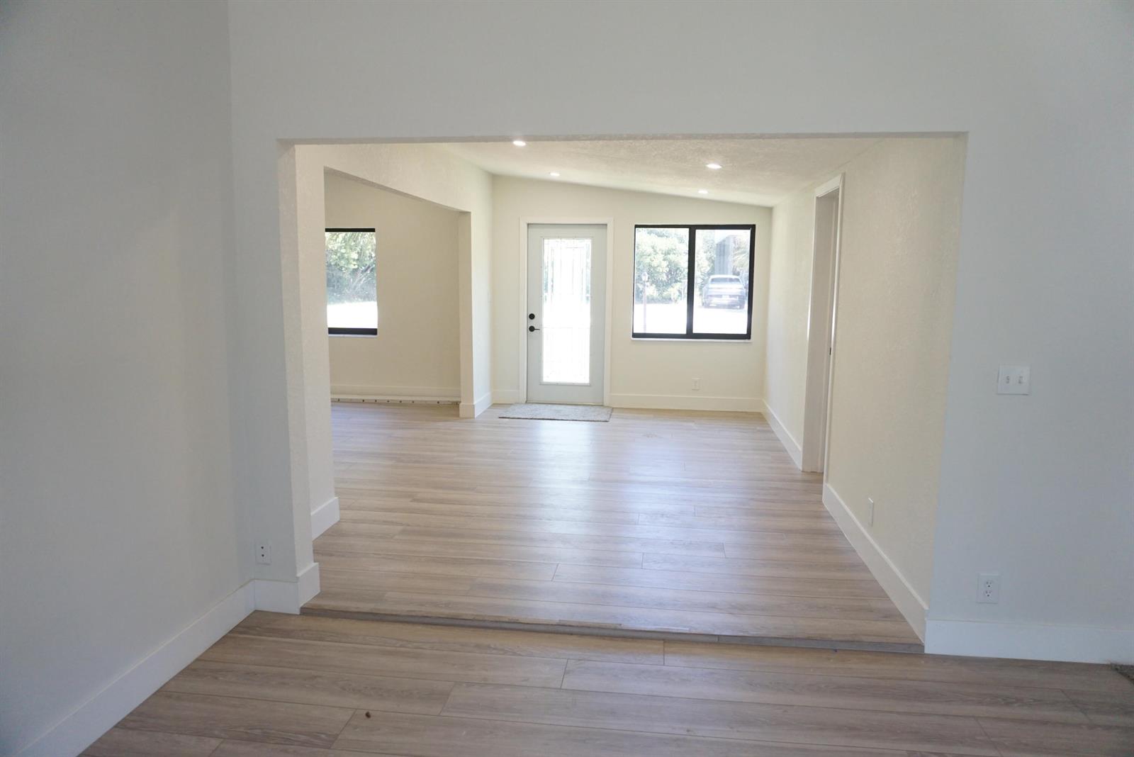 An interior view shows a living area with light wood flooring and a front door — 310 SW 1st Avenue, Boynton Beach FL 33435, BOYNTON BEACH, FL
