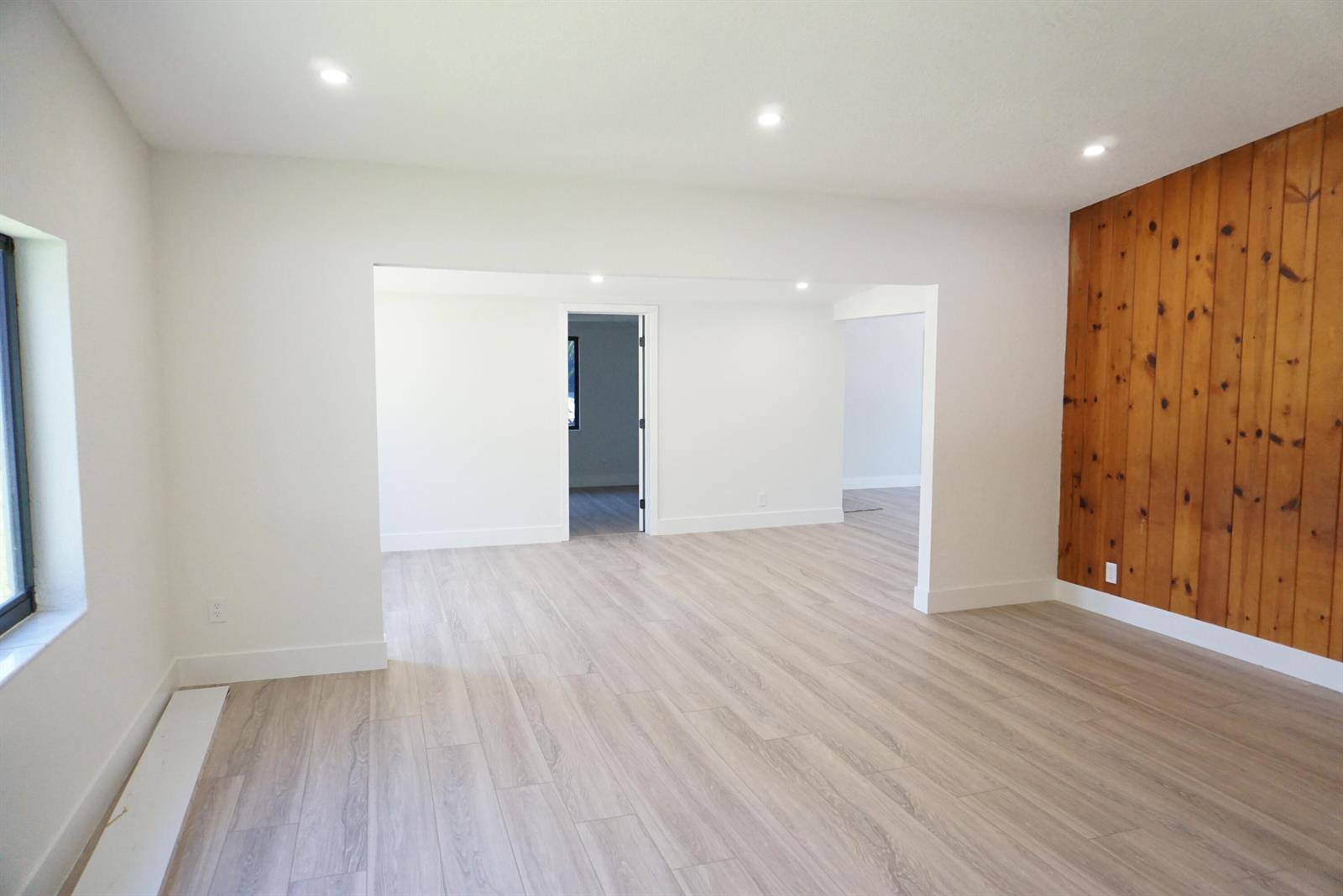 An empty room features light wood-look flooring, white walls, recessed lighting, and a wood-paneled wall — 310 SW 1st Avenue, Boynton Beach FL 33435, BOYNTON BEACH, FL