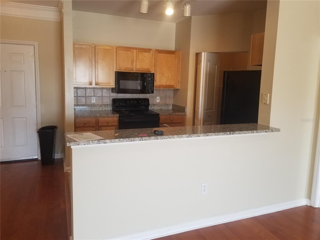 A kitchen features light wood cabinets, black appliances, and a granite-topped breakfast bar — 4207 S DALE MABRY HIGHWAY UNIT 2401, TAMPA, FL