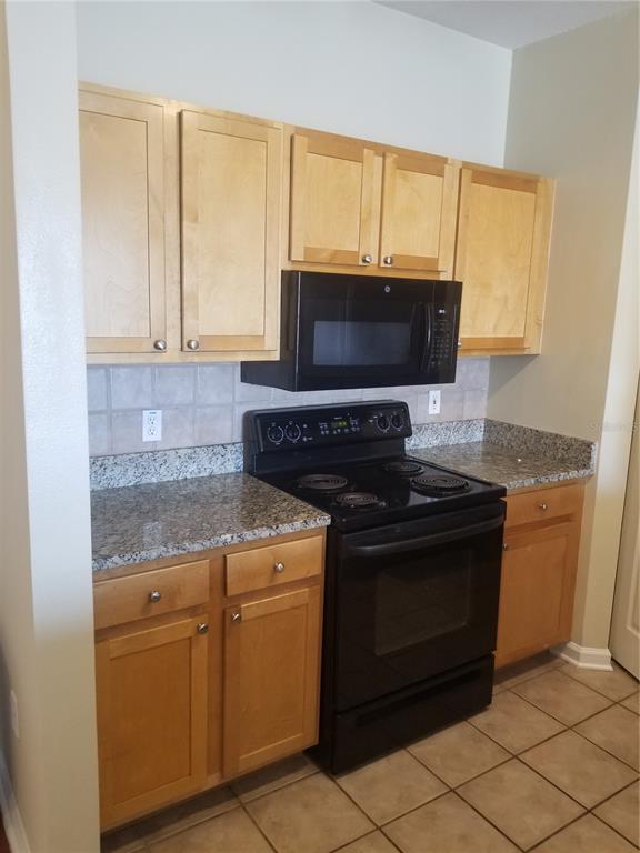A kitchen featuring light wood cabinets, granite countertops, and black appliances — 4207 S DALE MABRY HIGHWAY UNIT 2401, TAMPA, FL