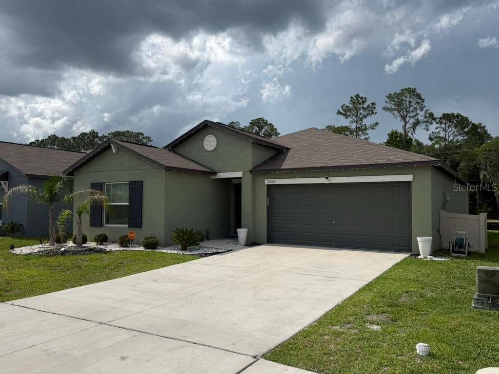 A single-story house with green stucco siding, a two-car garage, and a concrete driveway — 2000 RED LOOP, LAKELAND, FL