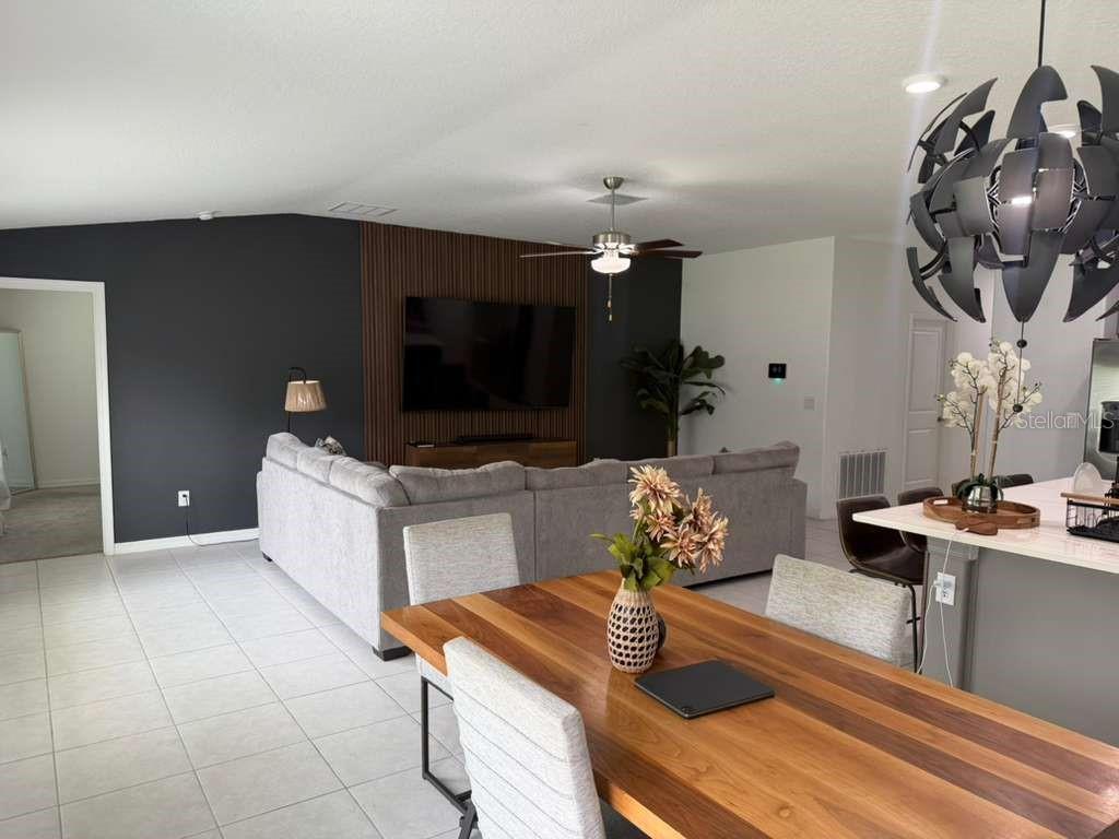 A living room and dining area feature a wood-slat accent wall, gray sofa, and chandelier — 2000 RED LOOP, LAKELAND, FL