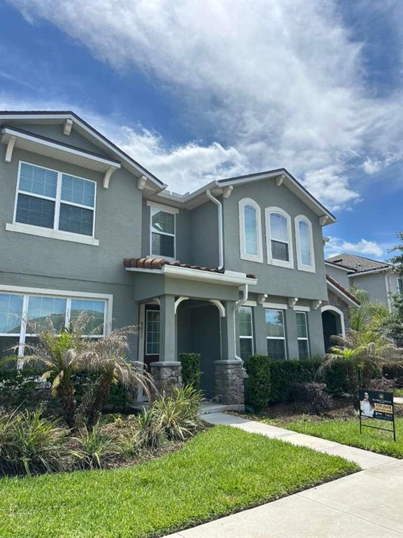 A two-story house with a gray stucco exterior, stone accents, and a covered front porch — 9031 LEGADO DRIVE, WINDERMERE, FL
