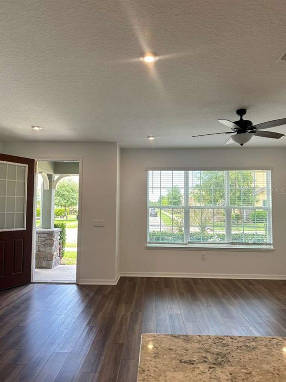 An interior view of a room with wood-look flooring, a ceiling fan, and a window — 9031 LEGADO DRIVE, WINDERMERE, FL